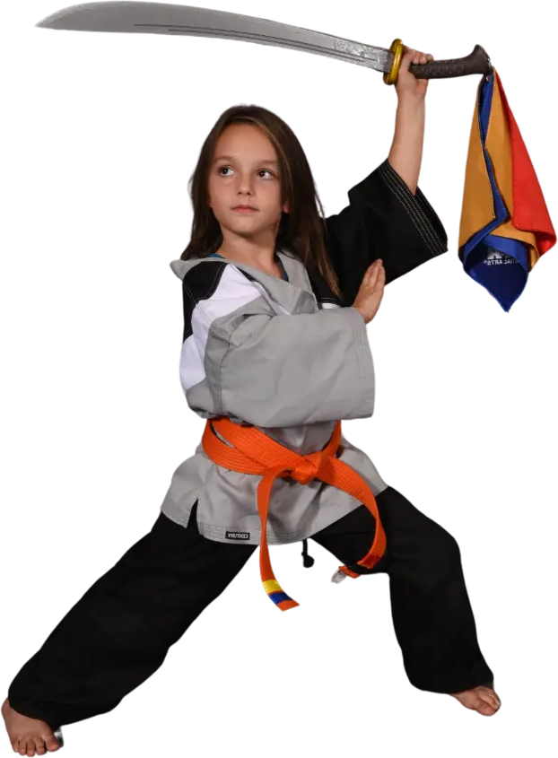 Young Tigers student in a black and grey uniform with an orange belt holding a training sword in a wide stance